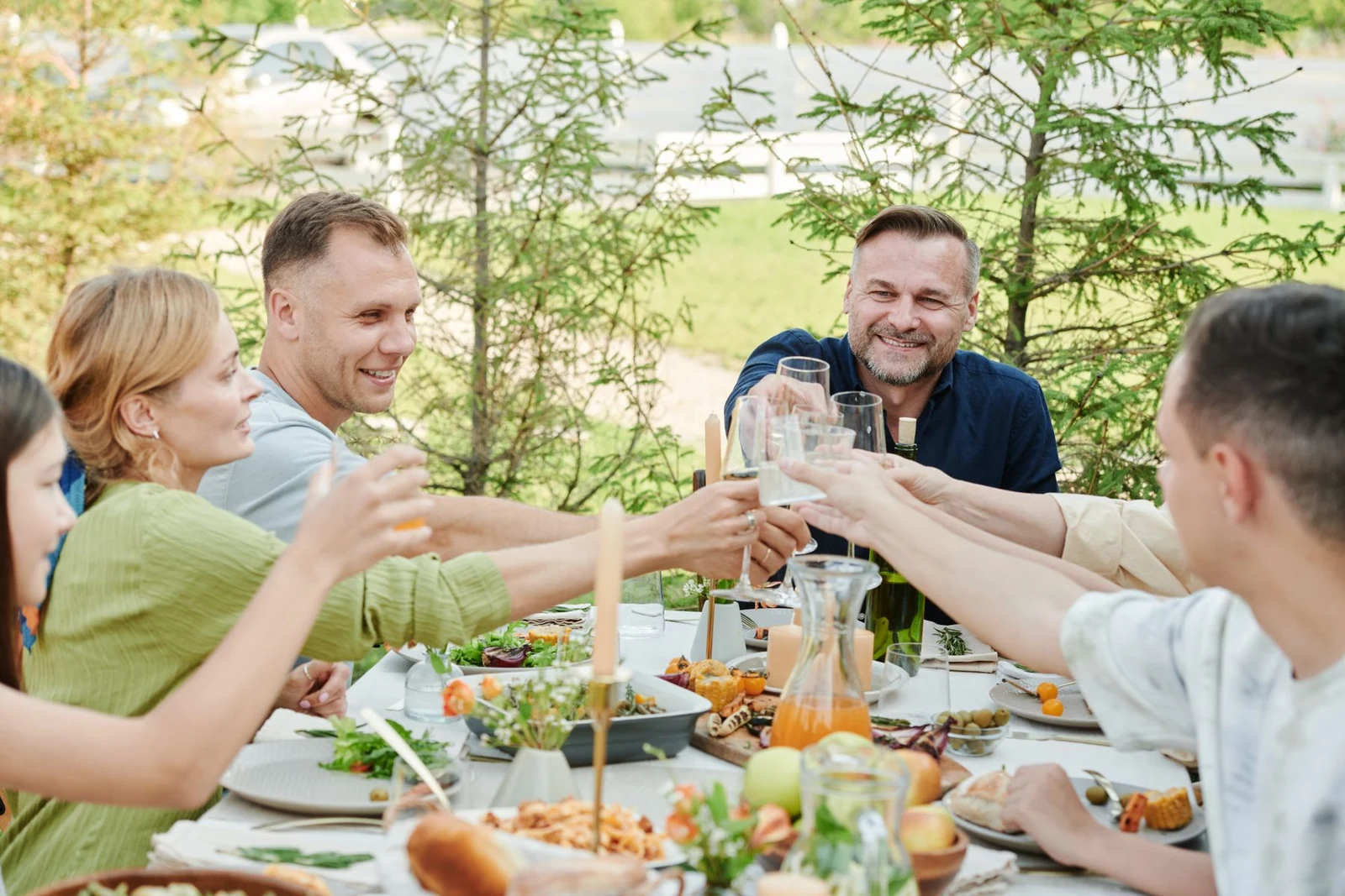 Smiling friends raising their glasses over a sunny garden meal