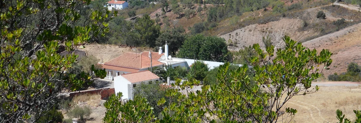 Village buildings, gardens and a dry hillside in the countryside near Alte.