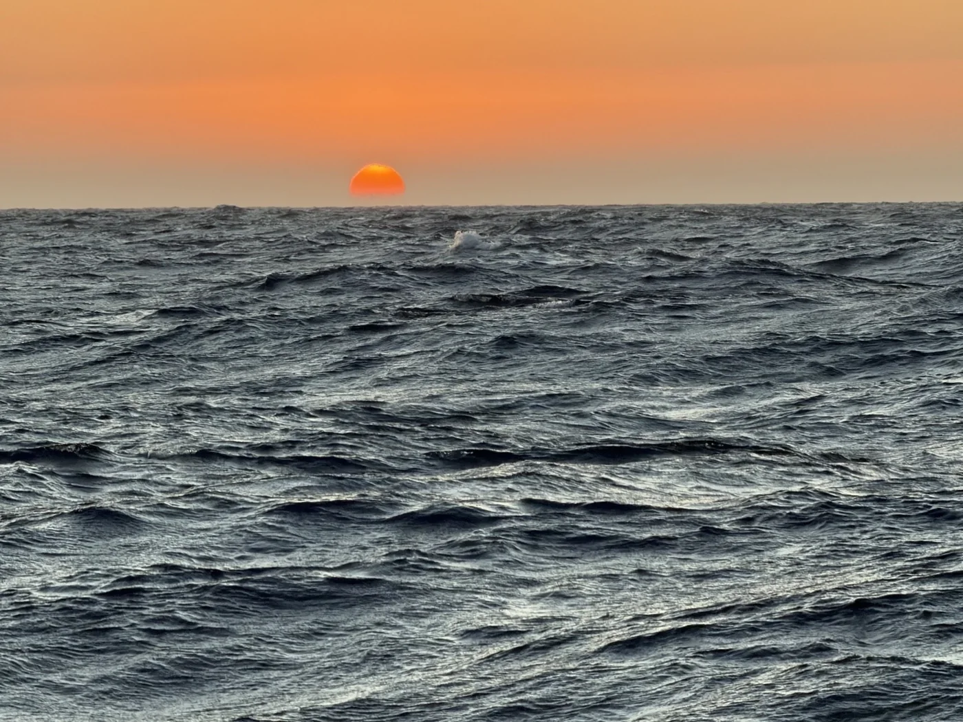 Sun setting over calm coastal water.