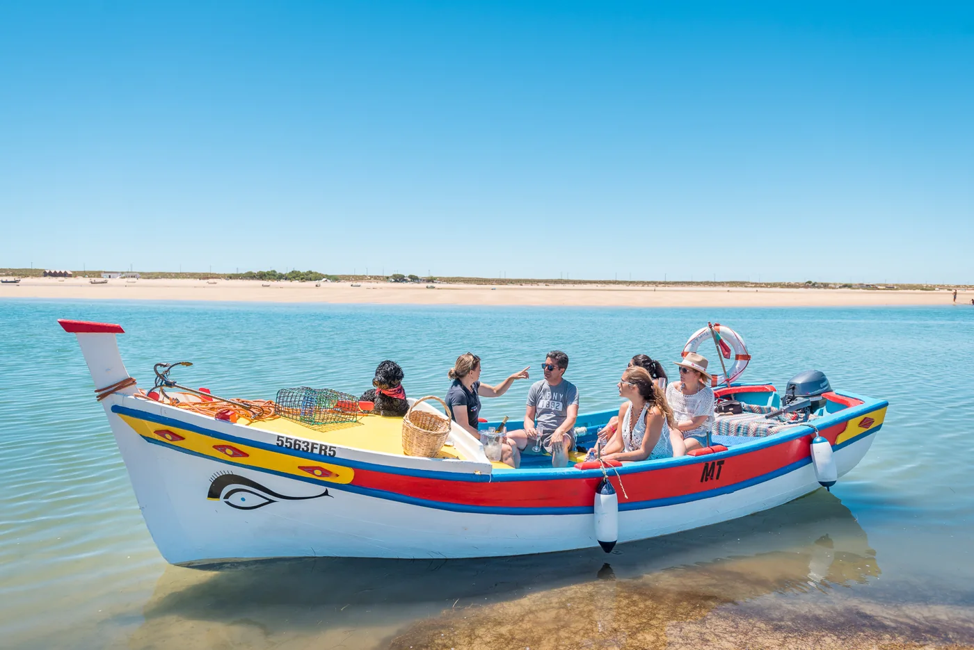 Guests aboard a traditional boat on calm coastal water.