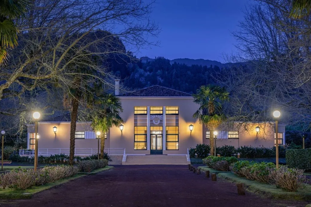 The illuminated Casino Terra Nostra building and garden at dusk.