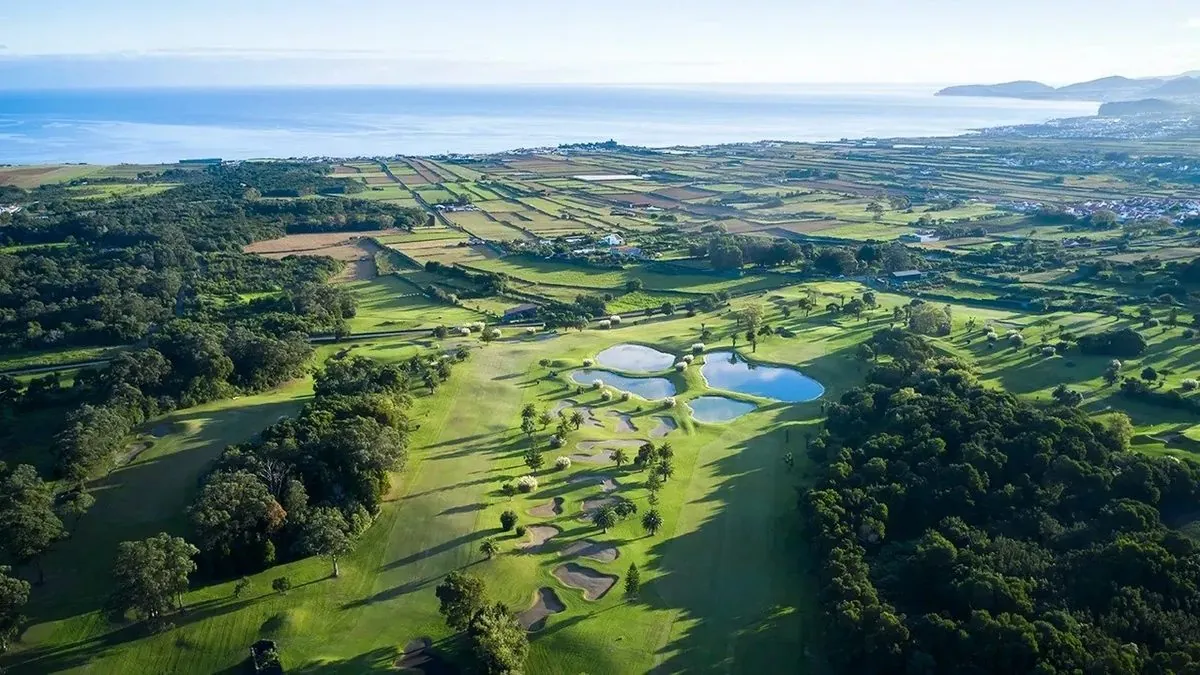 Rolling golf fairways and water hazards with the Atlantic coast in the distance.
