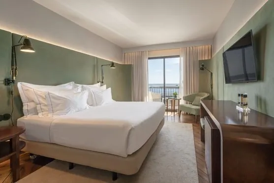 A double bedroom with seating and a marina-facing window at Grand Hotel Açores Atlântico.