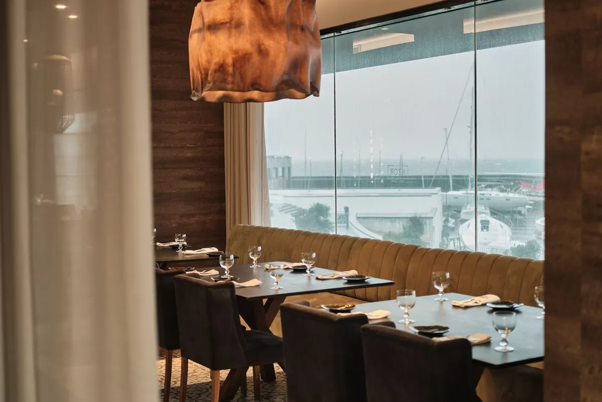 Restaurant tables beside harbour-facing windows at Octant Ponta Delgada.