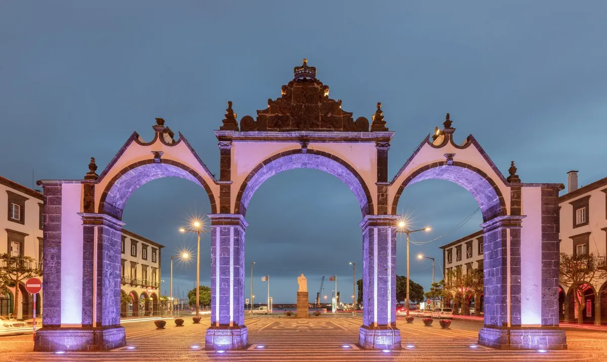 The three Portas da Cidade arches illuminated at dusk in Ponta Delgada.